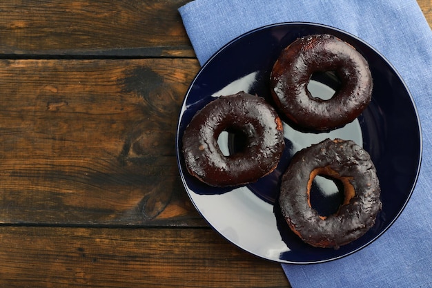 Delicious doughnuts with chocolate icing on table close up