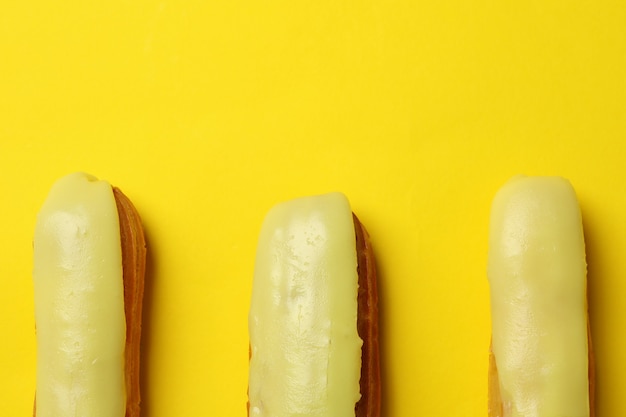 Delicious eclairs with custard on yellow background