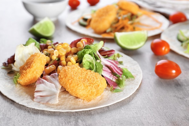 Delicious fish taco with filling on table close up