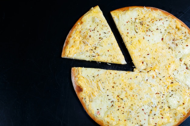 Photo delicious four cheeses pizza with cheddar, parmesan, mozzarella and tomato sauce on a black background. view from above.