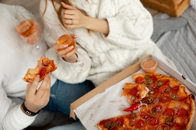 Delicious fragrant pizza and wine in glass glasses gives pleasure to couple in love on romantic date...