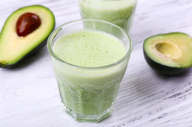 Delicious fresh avocado smoothie on white wooden background