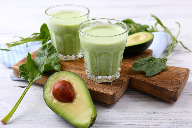 Delicious fresh avocado smoothie on white wooden background