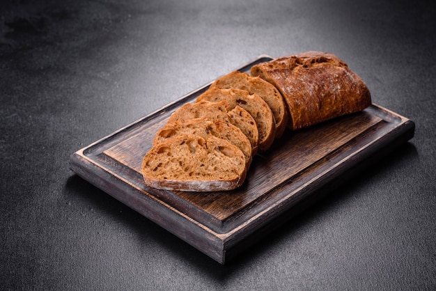 Delicious fresh black bread sliced with slices on a dark concrete background. Preparation of sandwiches