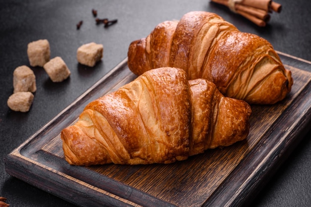 Delicious fresh crispy croissants on a dark concrete background. Tasty breakfast