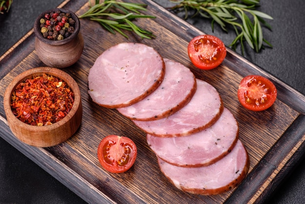 Delicious fresh ham cut with slices on a wooden cutting board on a dark concrete background