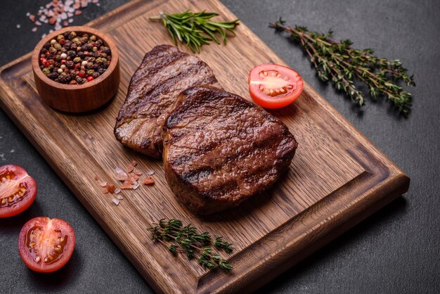 Delicious fresh juicy beef steak with spices and herbs on a dark concrete background