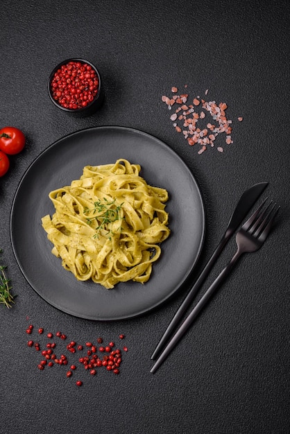 Delicious fresh pasta with pesto sauce salt spices and herbs on a ceramic plate on a textured concrete background