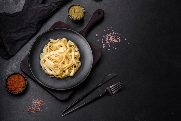 Delicious fresh pasta with pesto sauce and seafood on a black plate