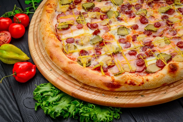 Delicious and fresh pizza with ham sausage and pickled cucumbers