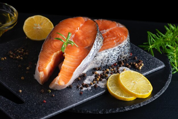 Delicious fresh salmon with lemon salt and spices on a black table Concept of healthy seafood