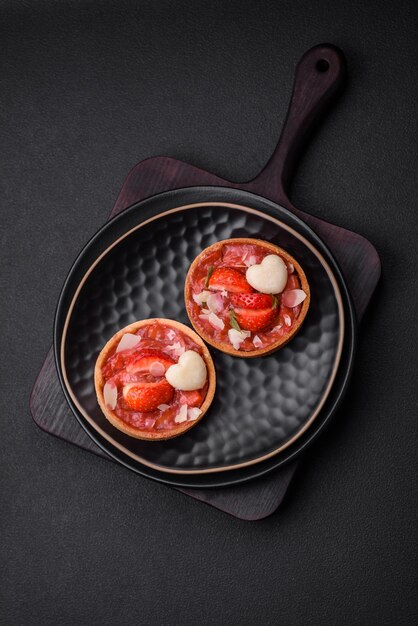 Delicious fresh sweet tartlets with strawberries and coconut flakes