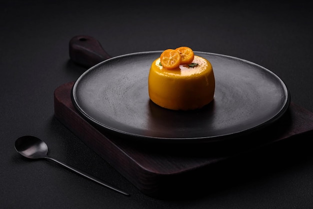 Delicious fresh tartlet with citrus filling and decorated with passion fruit on a black plate