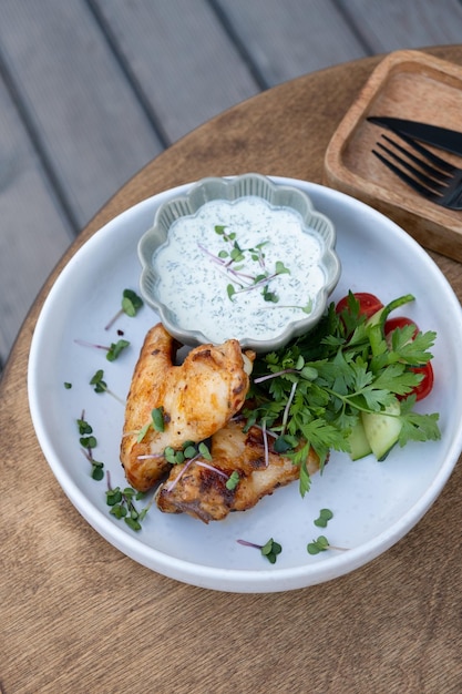 Photo delicious fried chicken wings with yogurt sauce and greens top view