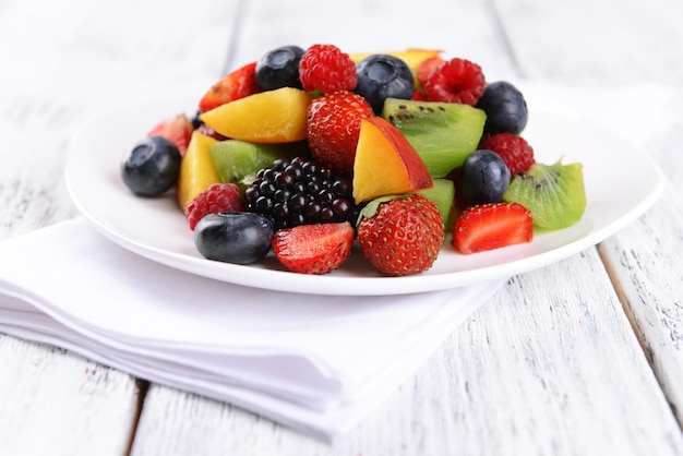 Delicious fruits salad in plate on table closeup