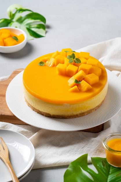 Delicious glazed mango no baked cheese cake with fresh diced mango pulp topping on bright table background