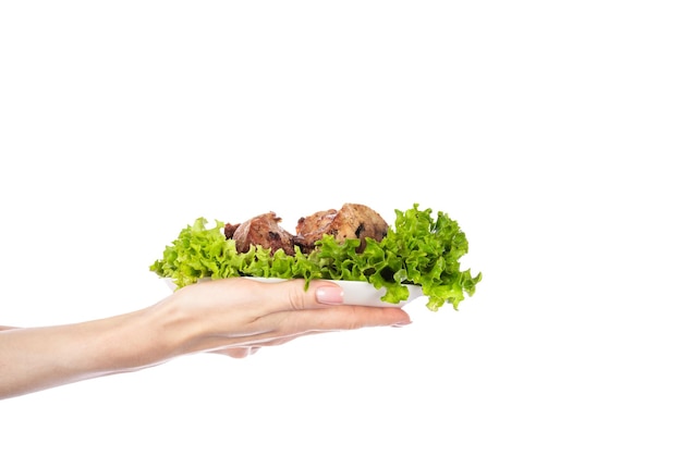 Delicious grilled meat with vegetable on white plate isolated on white background Meat in female hand