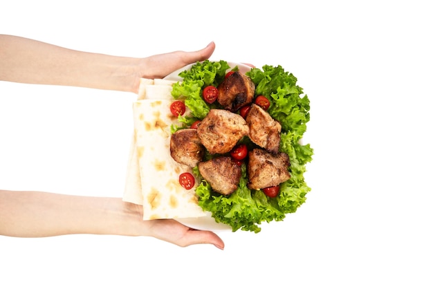 Delicious grilled meat with vegetable on white plate isolated on white background Meat in female hand