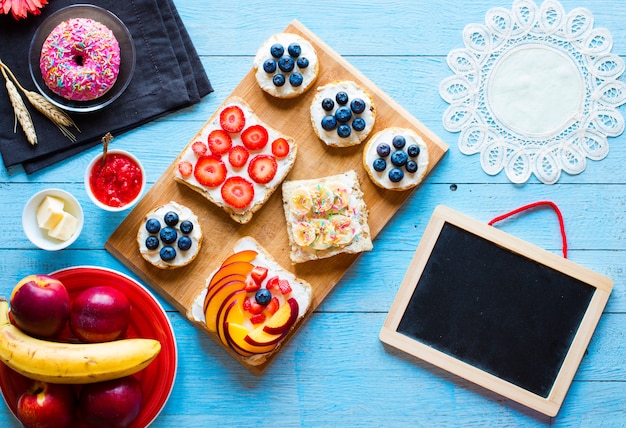 Delicious healthy breakfast, fruit sandwiches with different fillings, cheese, banana, strawberry, fishing, butter, blueberry, on a different wooden background.