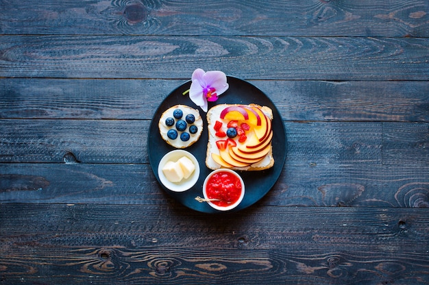 Delicious healthy breakfast, fruit sandwiches with different fillings, cheese, banana, strawberry, fishing, butter, blueberry, on a different wooden surface.