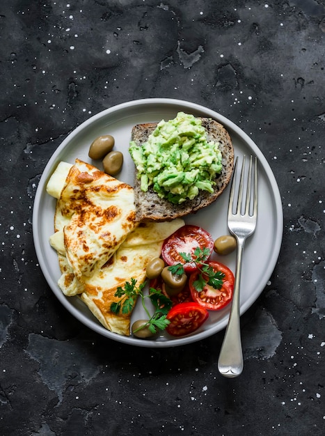 Delicious healthy breakfast omelette vegetables avocado toast on a dark background top view