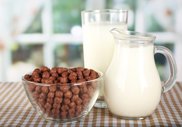 Delicious and healthy cereal in bowl with milk on table in room