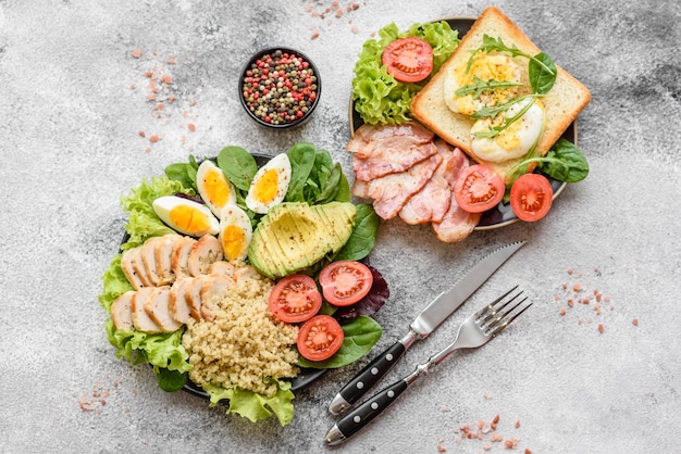 Delicious healthy lunch consisting of chicken avocado quinoa eggs tomatoes lettuce and greens on a black plate on a concrete background