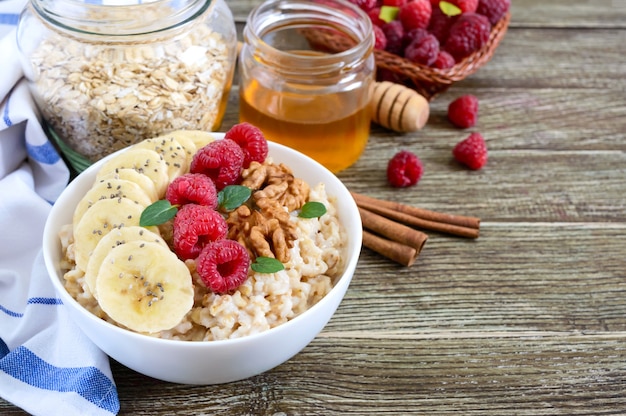 Delicious and healthy oatmeal with banana, raspberries, nuts. Healthy breakfast. Fitness food. Proper nutrition.