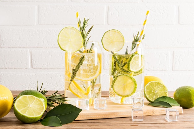 Delicious healthy soft drinks with slices of lime and lemon sprigs of rosemary and ice cubes on a hot day detox menu