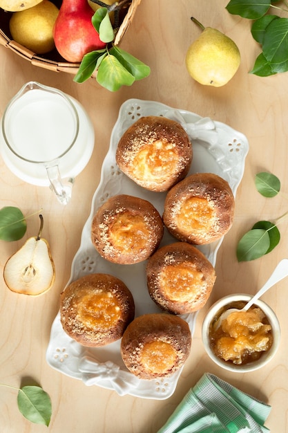 Delicious homemade buns with jam and fresh pears on a wooden background Mini pies Cooking recipe