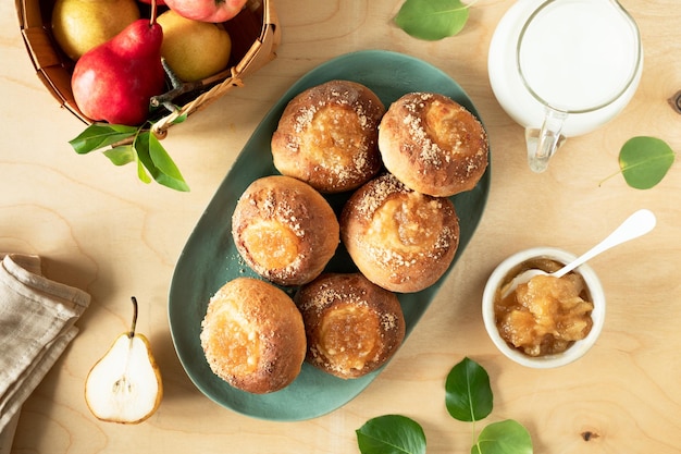 Delicious homemade buns with jam and fresh pears on a wooden background Mini pies Cooking recipe