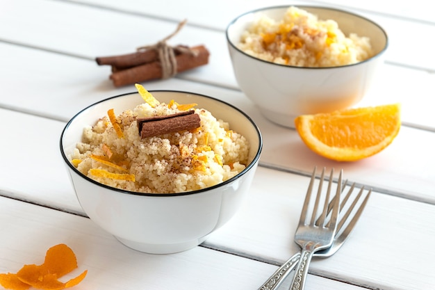 Delicious homemade couscous with oranges and cinnamon on rustic wooden background. Tasty vegan food.