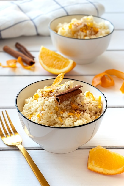 Delicious homemade couscous with oranges and cinnamon on rustic wooden background. Tasty vegan food.