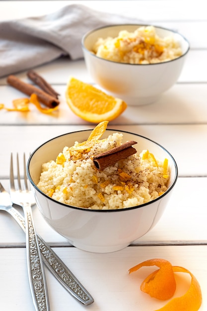 Delicious homemade couscous with oranges and cinnamon on rustic wooden background. Tasty vegan food.