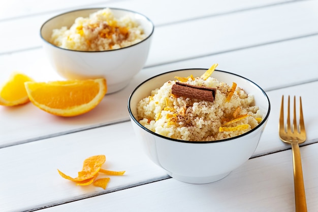 Delicious homemade couscous with oranges and cinnamon on rustic wooden background. Tasty vegan food.