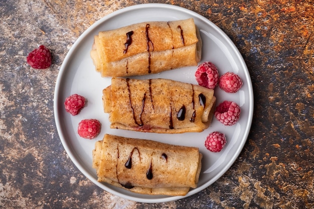 Delicious homemade crepes with raspberries and chocolate syrup