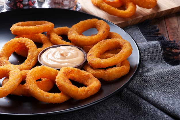 Delicious homemade crunchy fried onion rings with spicy sauce. Copy space