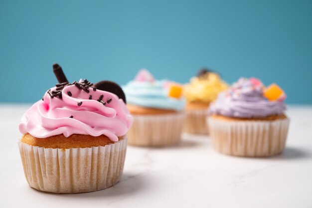 Delicious homemade cupcakes with Colorful cream and topping with candy and Chocolate Cookies.