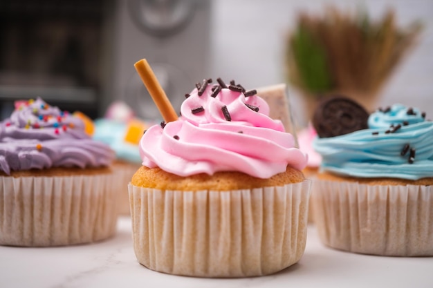 Delicious homemade cupcakes with Colorful cream and topping with candy and Chocolate Cookies