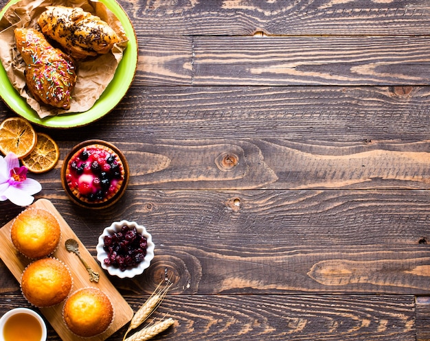 Delicious homemade muffins with yogurt on a wooden background with space for text.