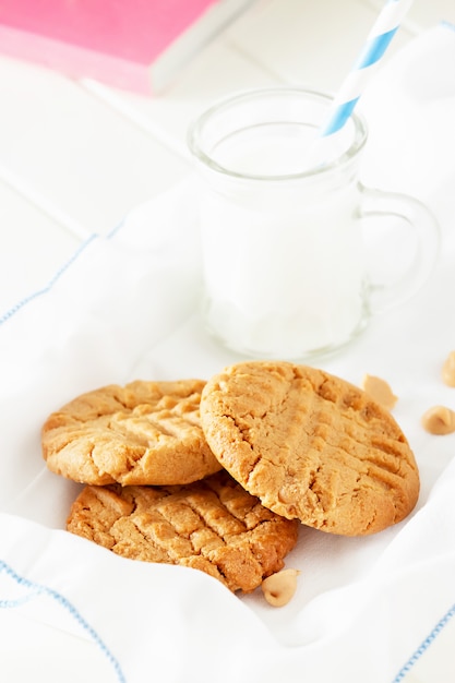 Delicious homemade peanut butter cookies with mug of milk. White wooden space. Healthy snack or tasty breakfast concept.