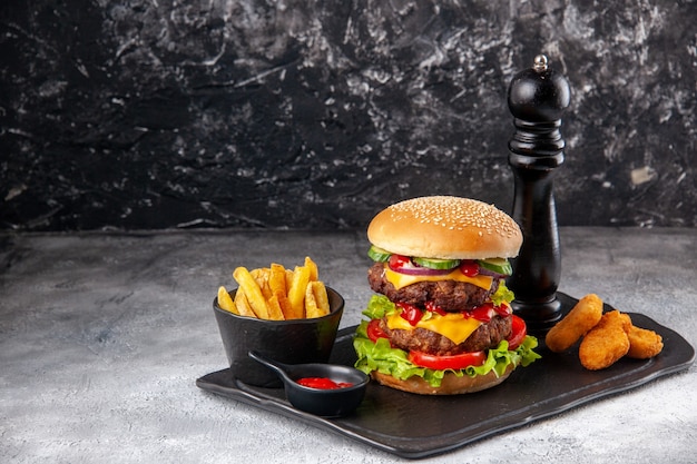 Delicious homemade sandwich and ketchup fries chicken nuggets on black board on the left side on gray distressed surface