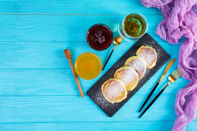 Delicious homemade syrniki with strawberry jam and honey Traditional russian dish syrniki Top view