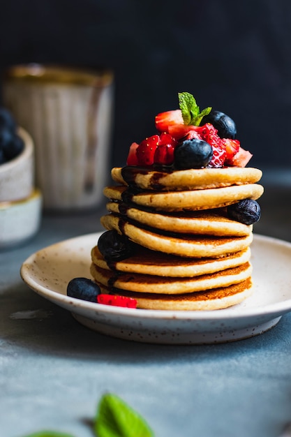 Delicious homemade vegetarian oat pancakes with blueberry, strawberry, mint and chocolate sauce