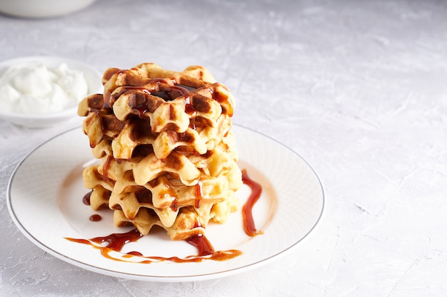 Delicious homemade waffles served in white plate on a white table