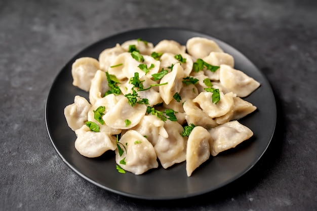 delicious homemade whole-wheat flour dumplings or Russian dumplings sprinkled with fresh parsley on a plate on a wooden table, copy space, top view