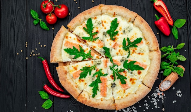 Delicious hot pizza with salmon arugula and different spices on wooden table ready to eat