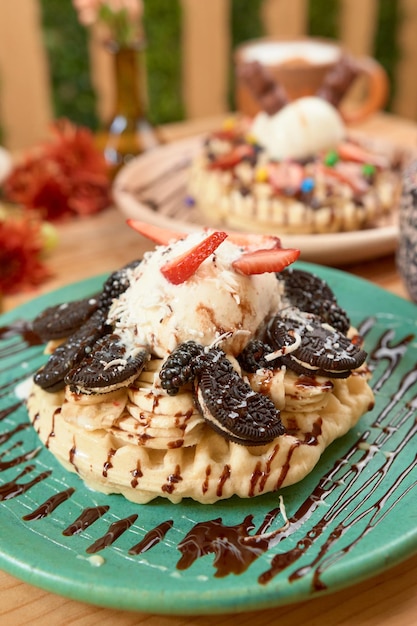 Delicious ice cream waffle with chocolate and cookies on wooden table