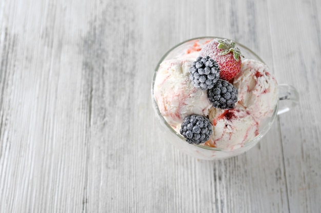 Delicious ice cream with fresh frozen berries on color wooden background