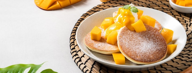 Delicious Japanese souffle pancake with dice mango and jam on gray table background